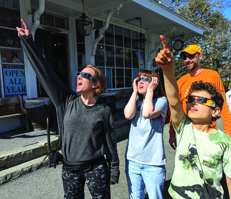 A family checks out the full solar eclipse Monday afternoon outside the Brewster General Store. Behind the eclipse glasses are (from left) Jessica, Jana and Randy Tannatt; waiting for his turn is dad Samuel. ALAN POLLOCK PHOTO