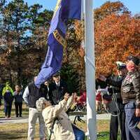 Flags were raised to honor the six branches of the armed services; releasing the U.S. Navy flag is 98-year-old Helen Sanford, a WAVE from World War II.