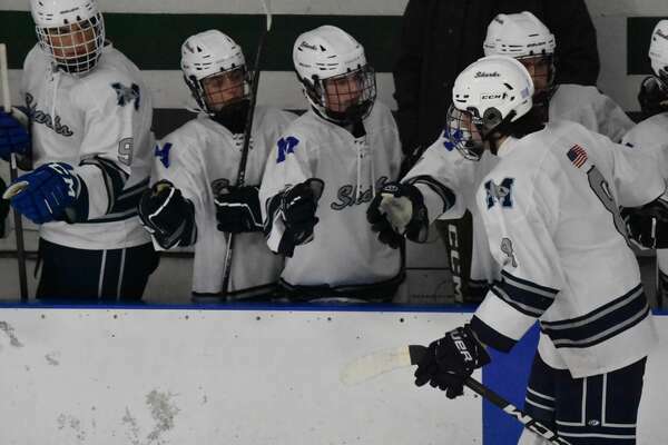 Monomoy sophomore defenseman Luke Raftery high fives teammates after scoring the team’s first goal.