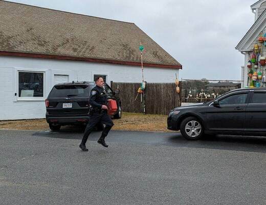 An Orleans Police Officers runs toward the scene with an automatic defibrillator. ALAN POLLOCK PHOTO